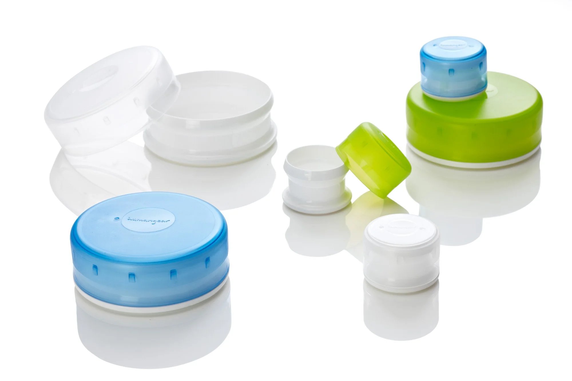 Assorted Humangear GoTubb containers on a reflective surface; includes containers in white, blue, and green colors.