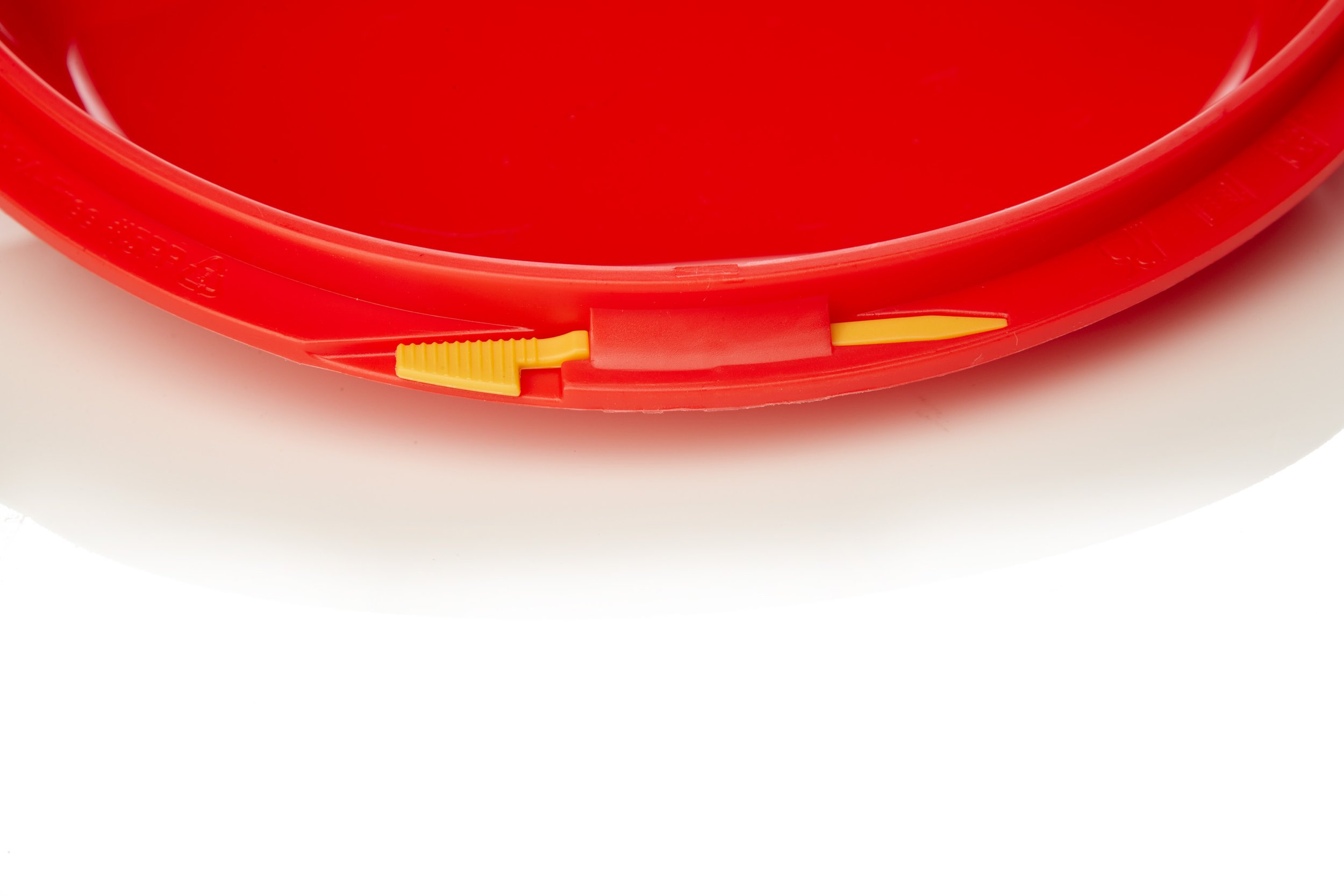 Close-up of a red plastic bucket with a yellow pouring spout on the rim.