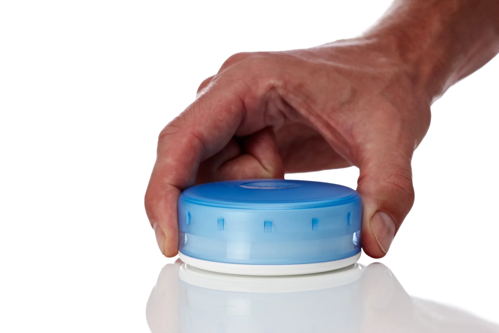 Hand holding a blue plastic container lid on a white surface