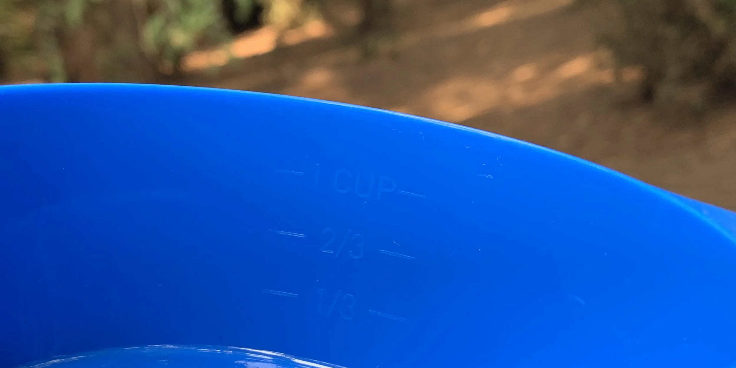Close-up of a blue measuring cup with markings for 1 cup, 2/3 cup, and 1/3 cup.
