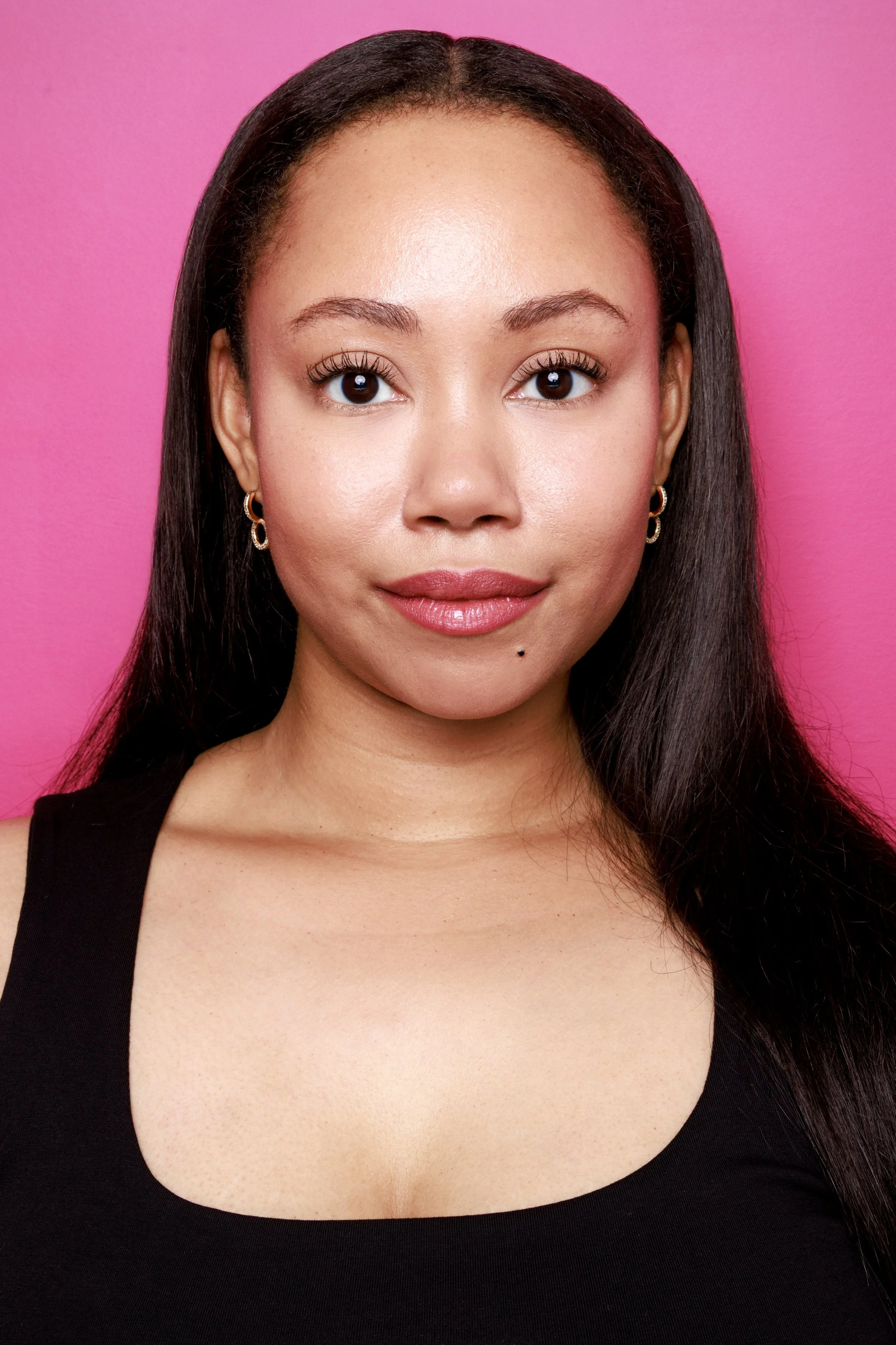 Vittoria Marlone with a pink background in a black shell tank top