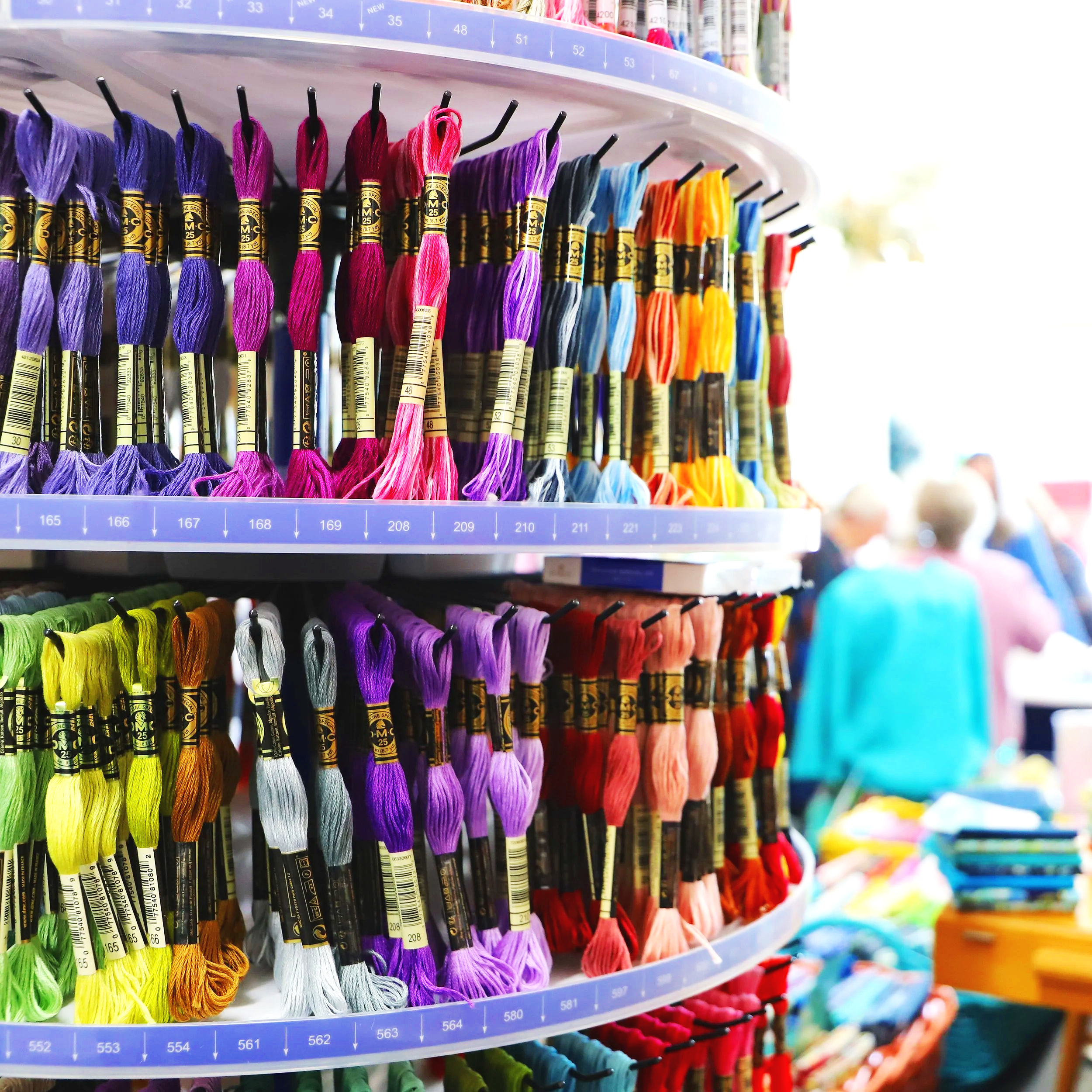 Spools of colorful embroidery floss arranged on a rotating display shelf at a craft store.