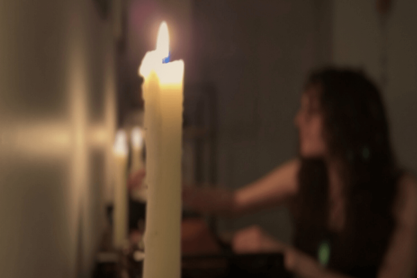 Ariel working at her altar space, with a candle in the foreground