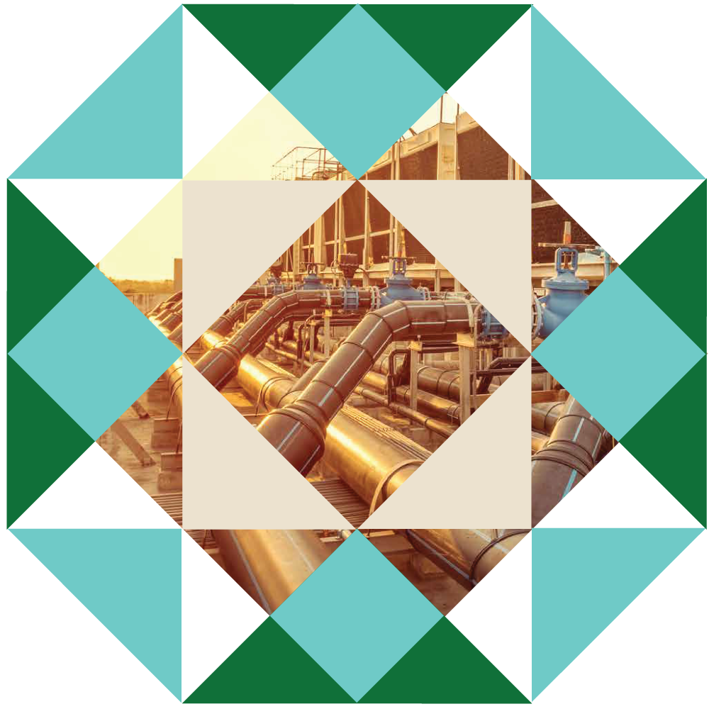 Industrial pipes and infrastructure at sunset with building in background.