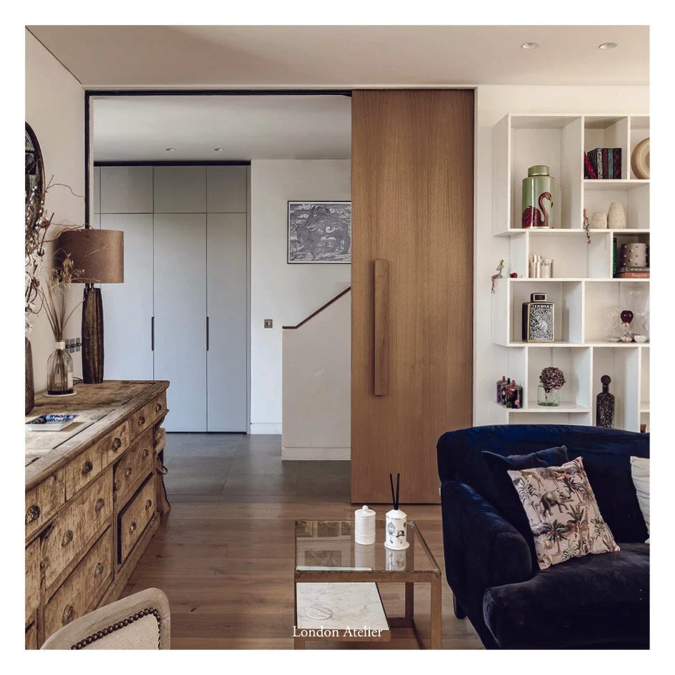 A large sliding wooden clad fire door allows the staircase to be closed off from the open-plan ground floor kitchen and living spaces. When open, it reveals the warm, softly lit entrance hall and opens up a view to the staircase zone with the rest of