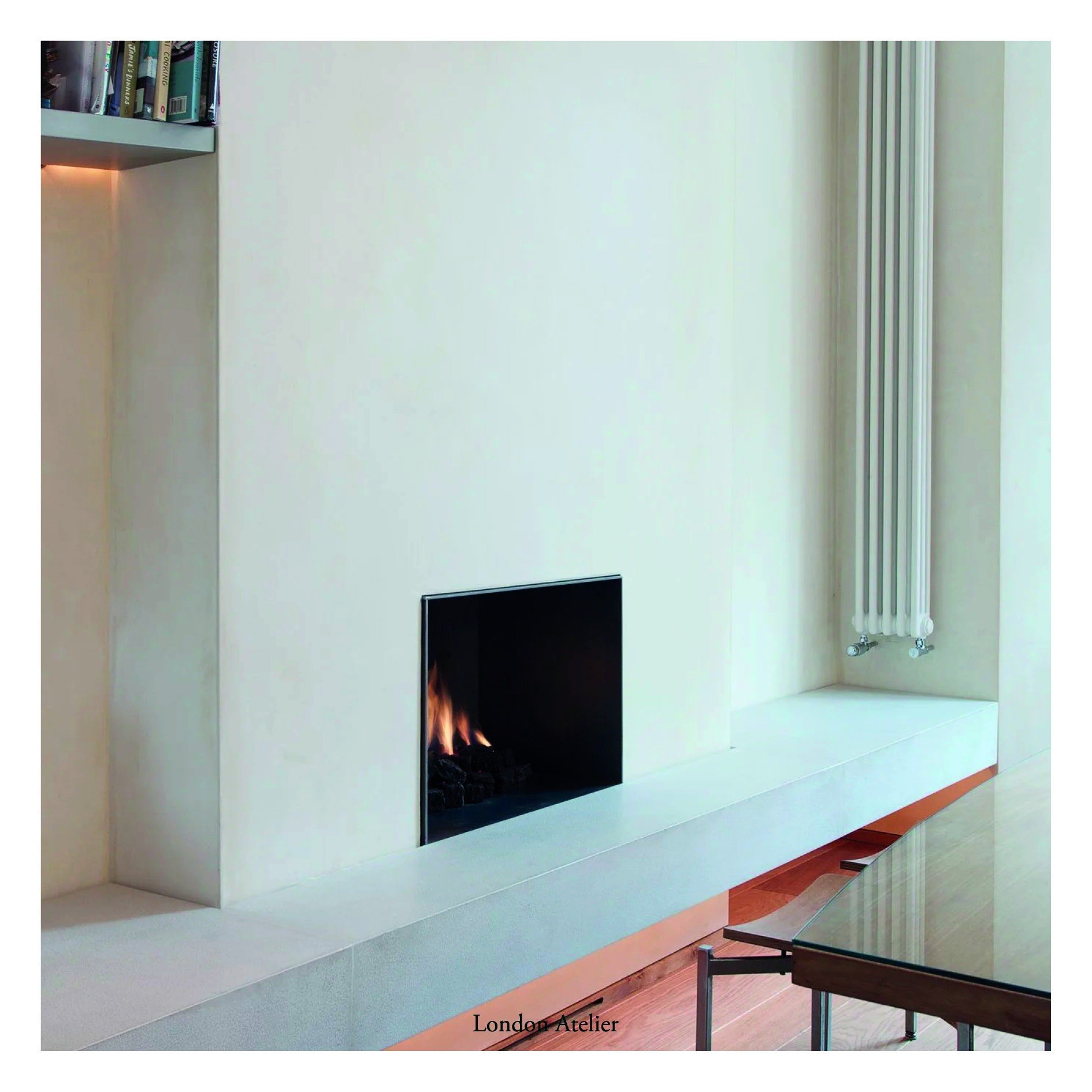 A Victorian terrace in Chelsea converted from two flats back into a single family home. The kitchen centres around a reactivated fireplace with a modern stone bench, while pigmented plaster and oak flooring balance period details with contemporary li