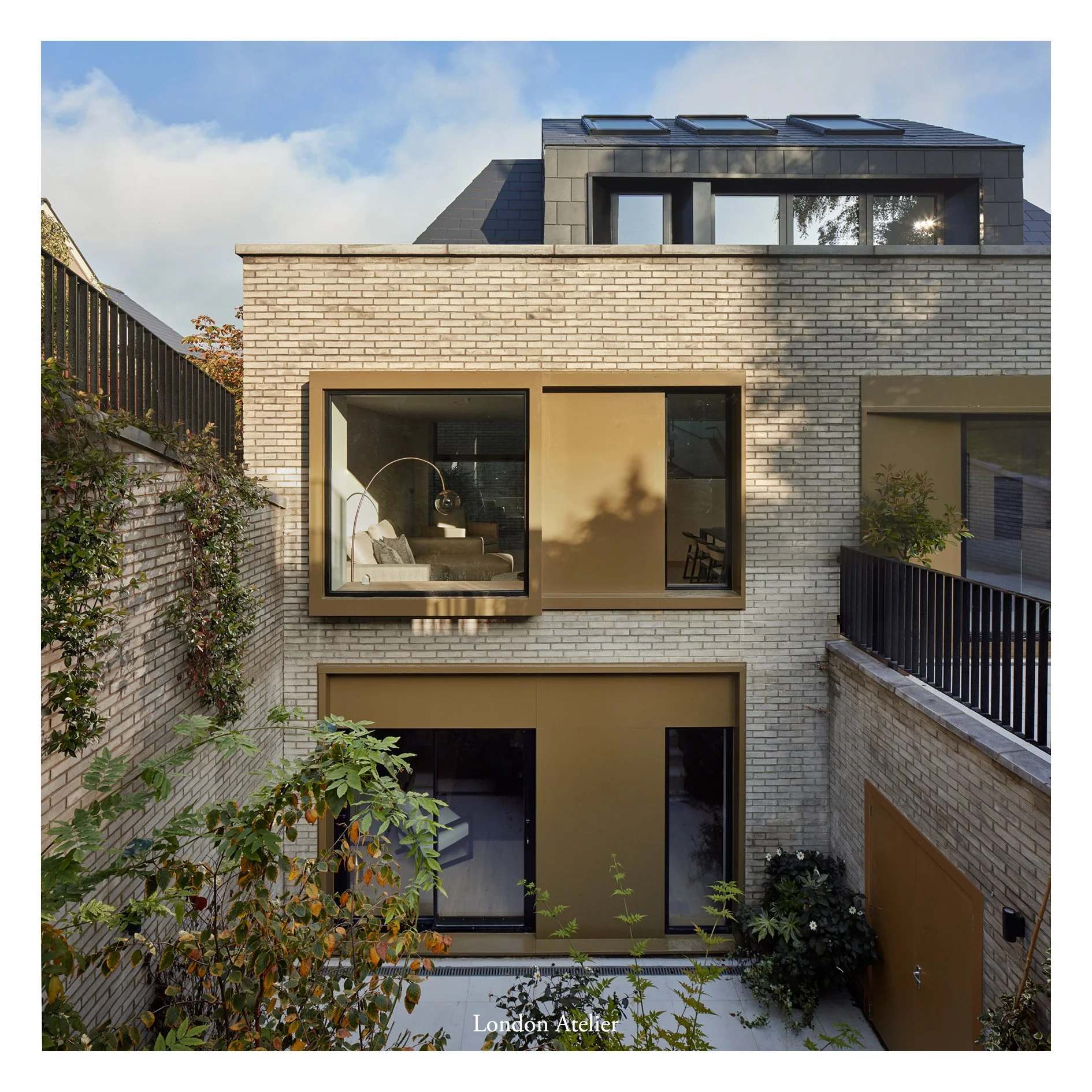 A new build three-story family home set into a steep hill in Sevenoaks. The established mass is split into two halves connected via a central glazed link, forming six distinct split levels that follow the slope of the hill. This glazed connection all