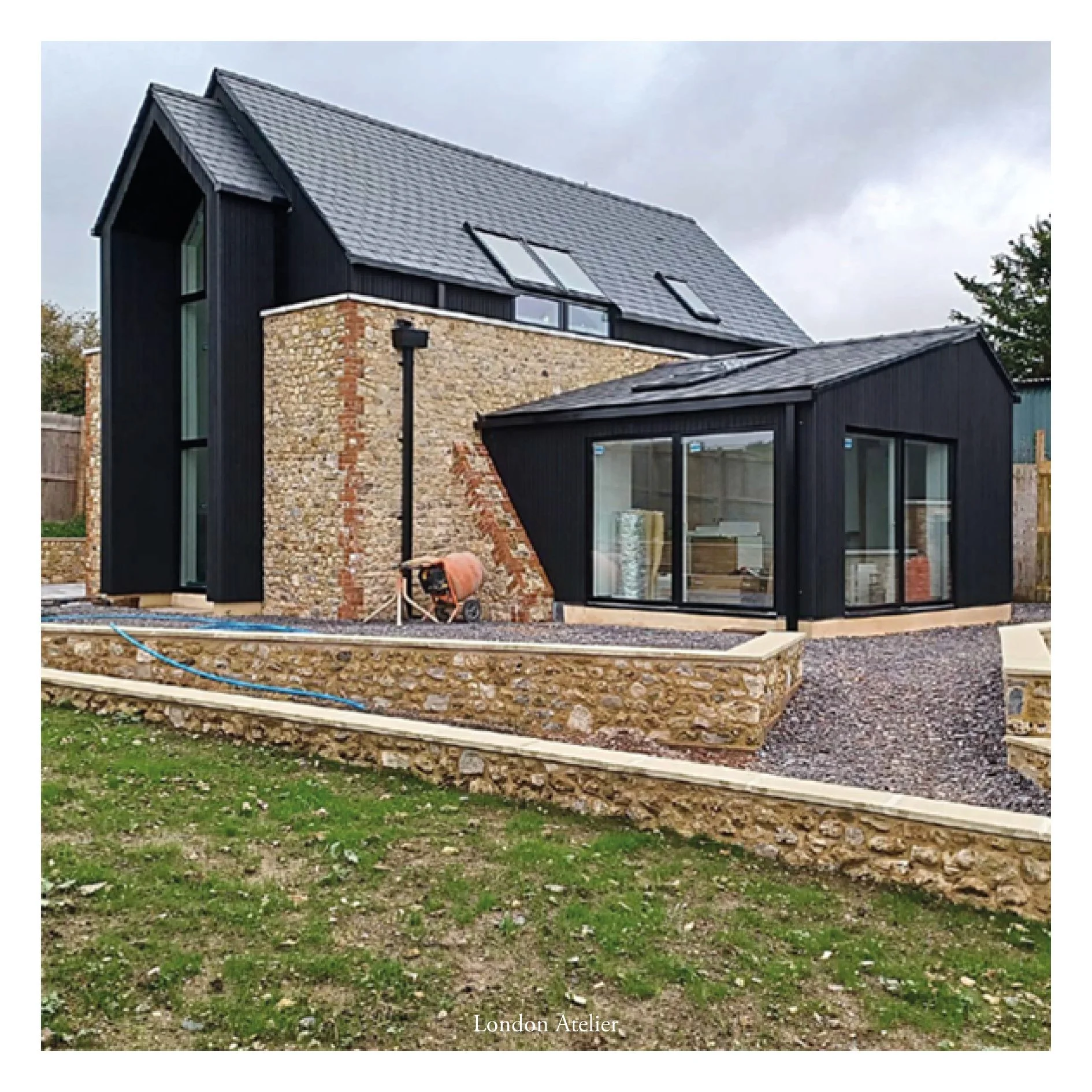 Two barn conversions set within the remnants of historic stone walls on a Grade II listed estate in Somerset. Pre-fabricated cedar-clad panels rise from within the existing walls, while double-height south-facing glazing offers spectacular views over