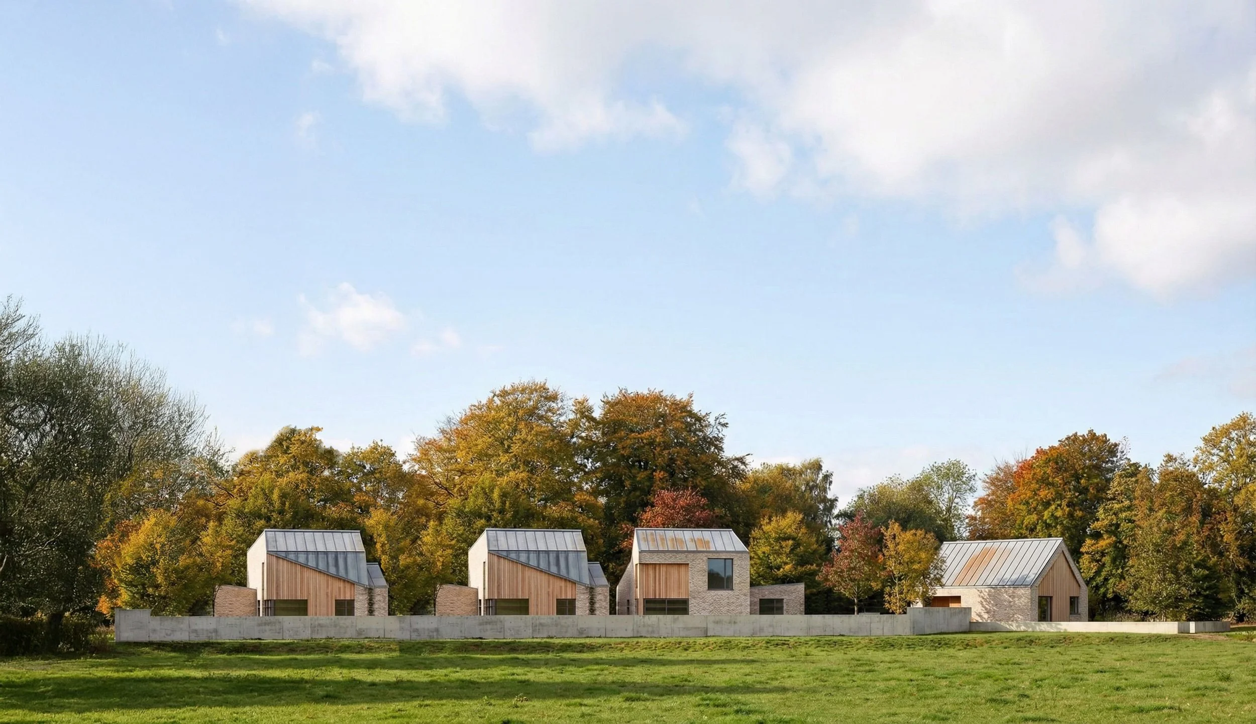 Long view of contemporary houses with pitched metal roofs and timber-clad gables, arranged along a landscaped boundary and framed by mature trees.