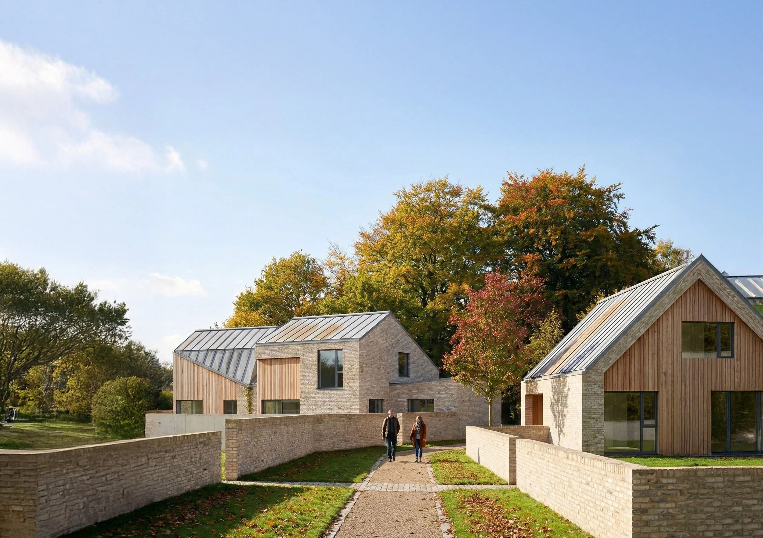 Entrance view showing contemporary brick houses with timber-clad gables and standing-seam metal roofs, arranged along a landscaped pedestrian path between low brick walls.
