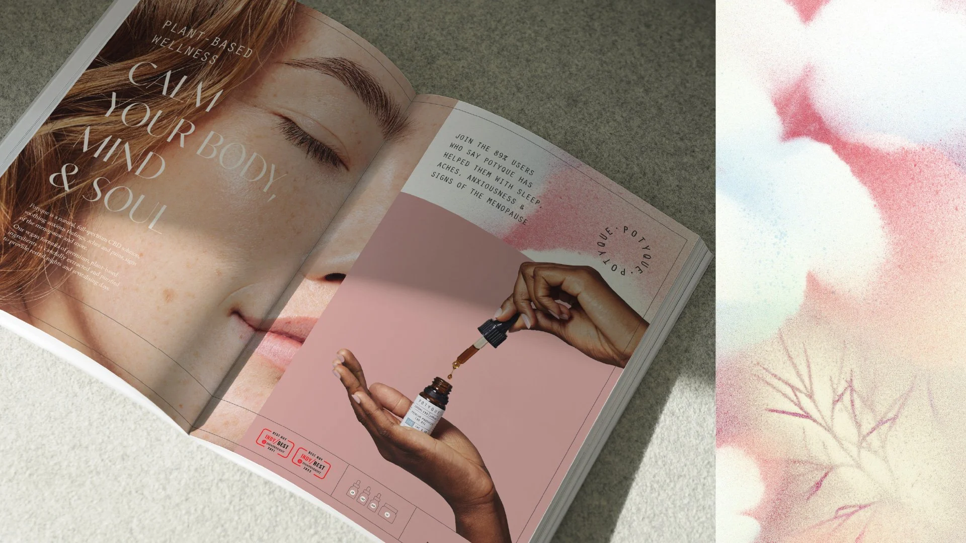 Open magazine displaying a close-up image of a woman's face with freckles, and an article about plant-based wellness. The page features a woman’s hand holding a dropper with a small bottle, demonstrating a skincare or supplement product. The background includes soft, pink, and white abstract floral patterns.