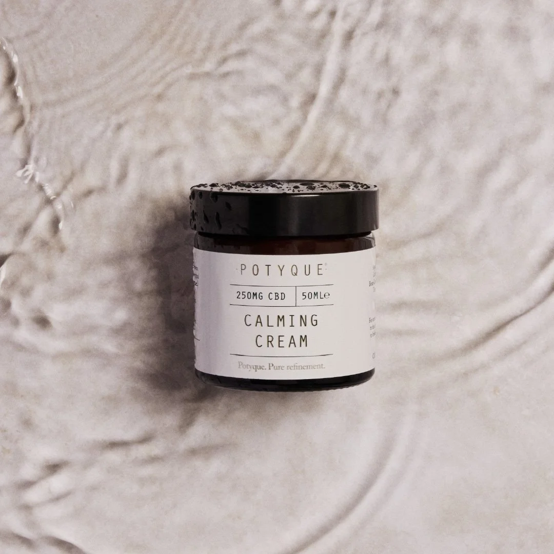 A jar of Potyque Calming Cream with CBD, 250mg, 50ml on a textured beige surface.