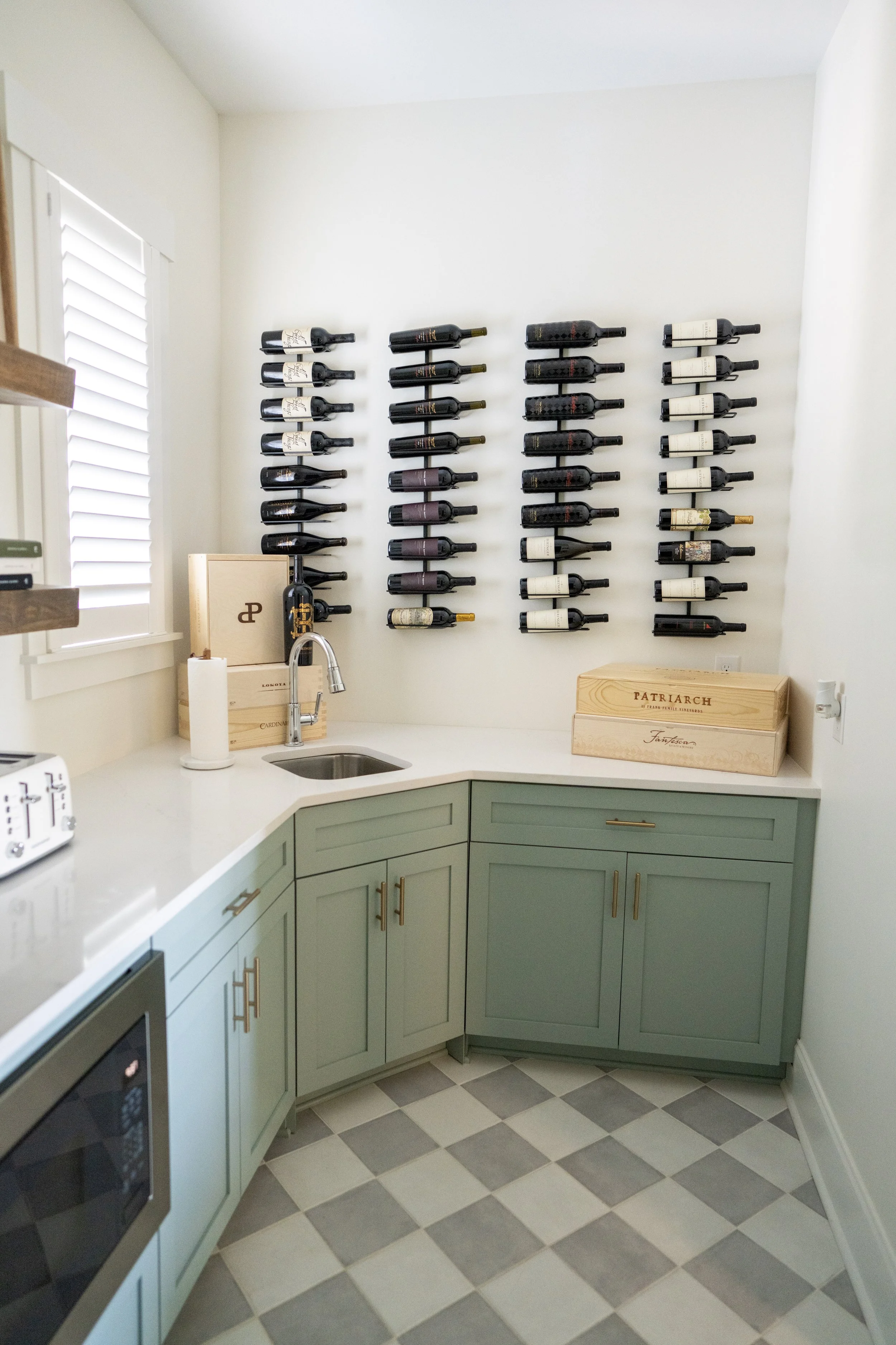 Kitchen with wall-mounted wine bottle rack and green cabinets.