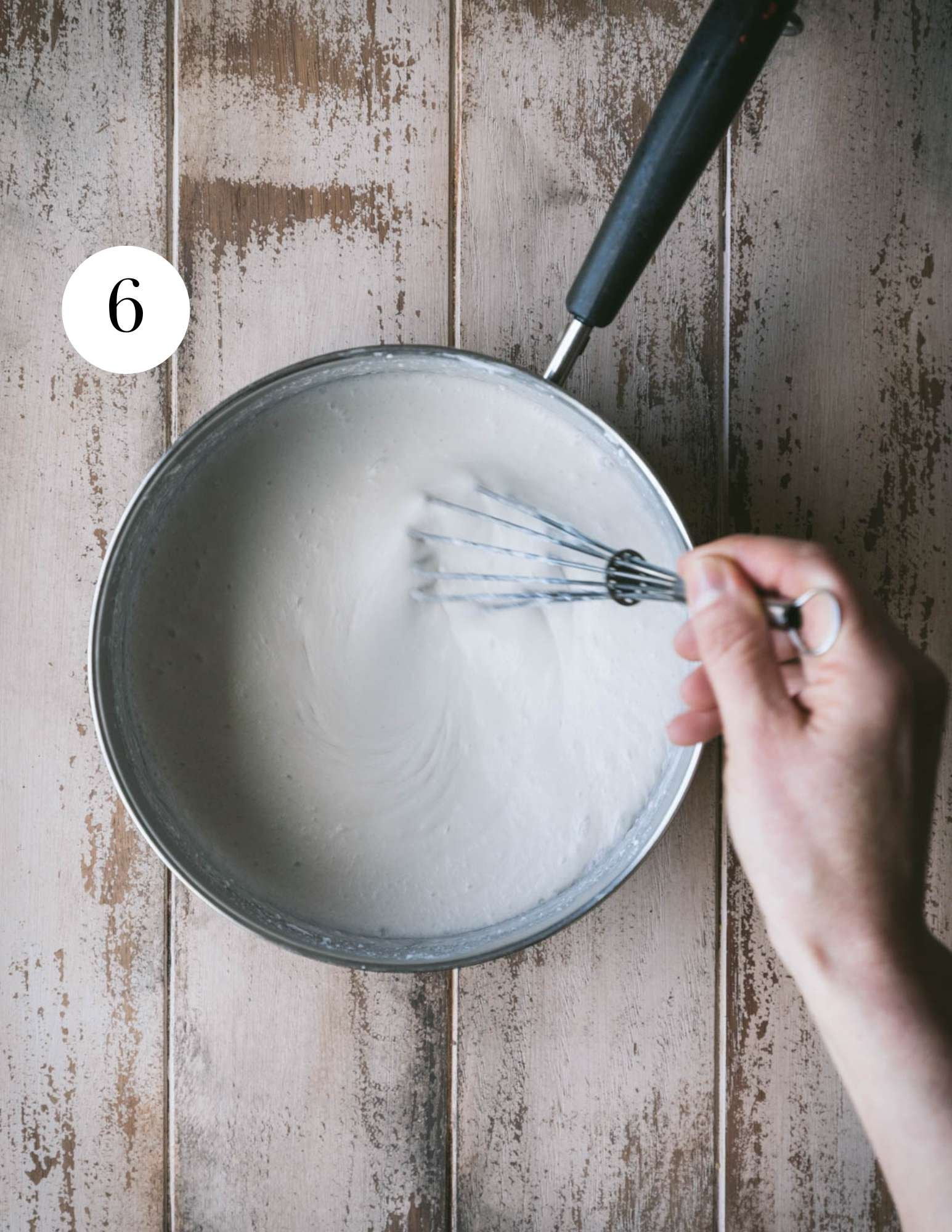 Whisking coconut milk in a saucepan.