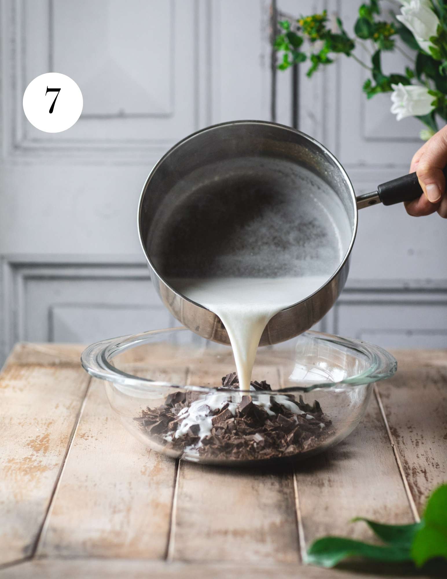 Pouring hot coconut milk over chopped chocolate.