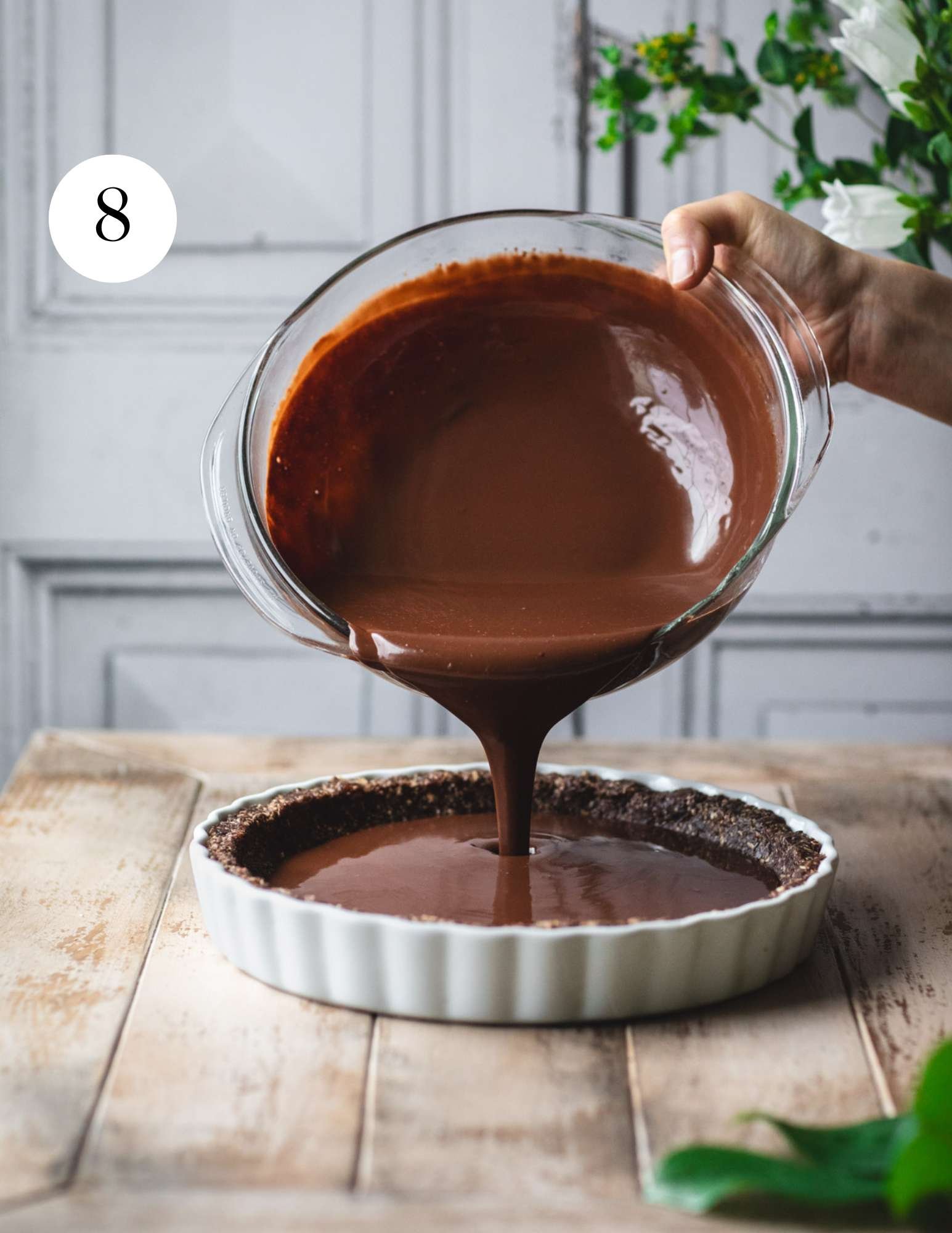 Pouring chocolate ganache into a tart crust.