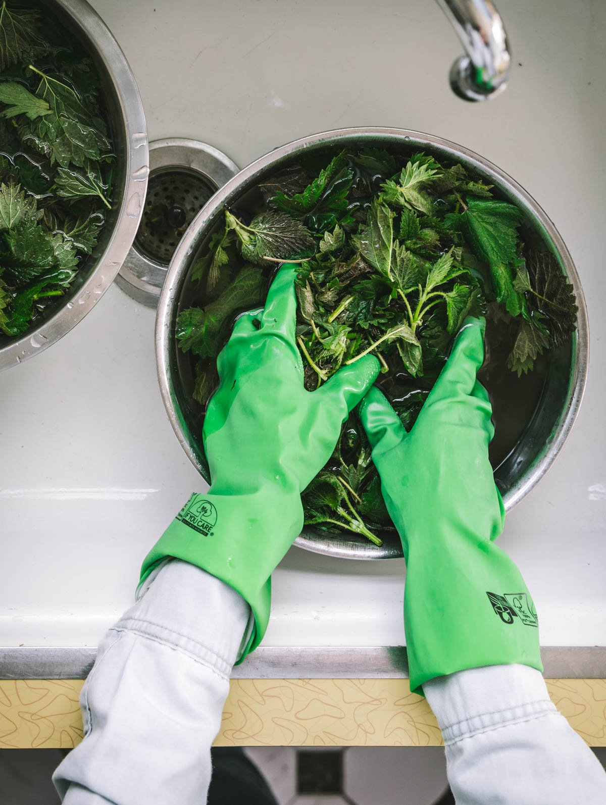 Washing stinging nettles in a bowl in the sink.