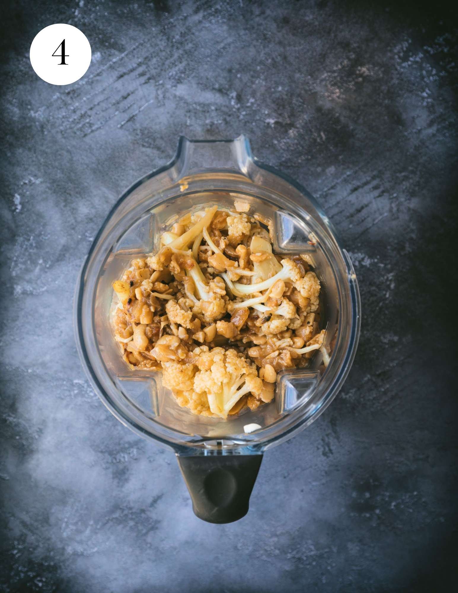 Cauliflower and cashews in a blender container.