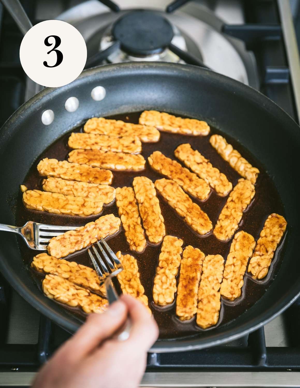 Tempeh slices in bacon sauce in a pan.