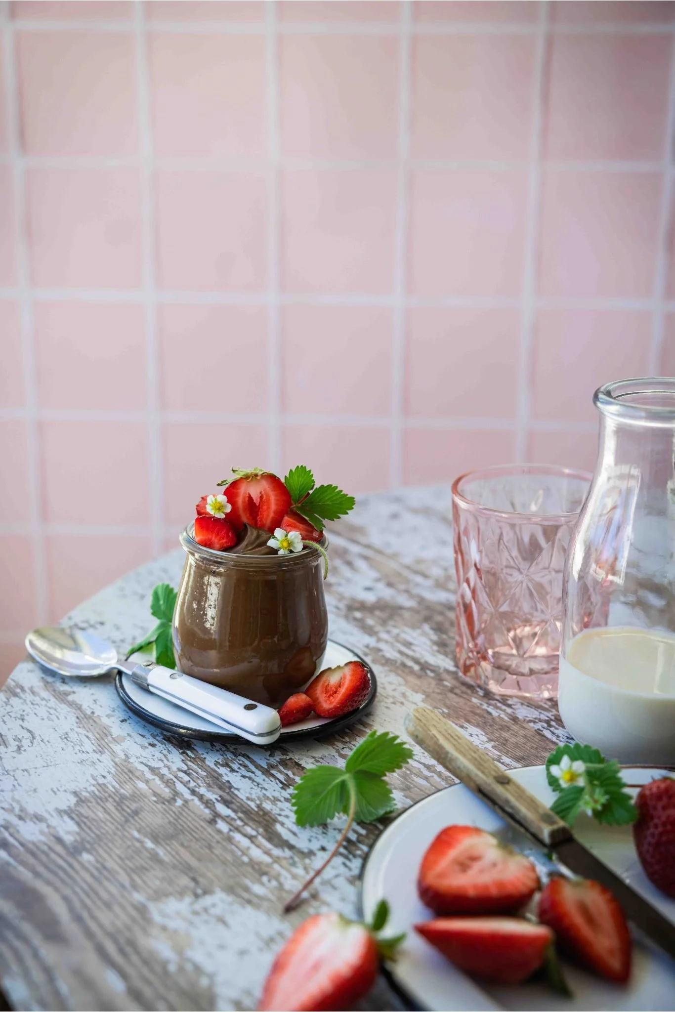 vegan avocado chocolate mousse in a jar next to a plate of fresh berries