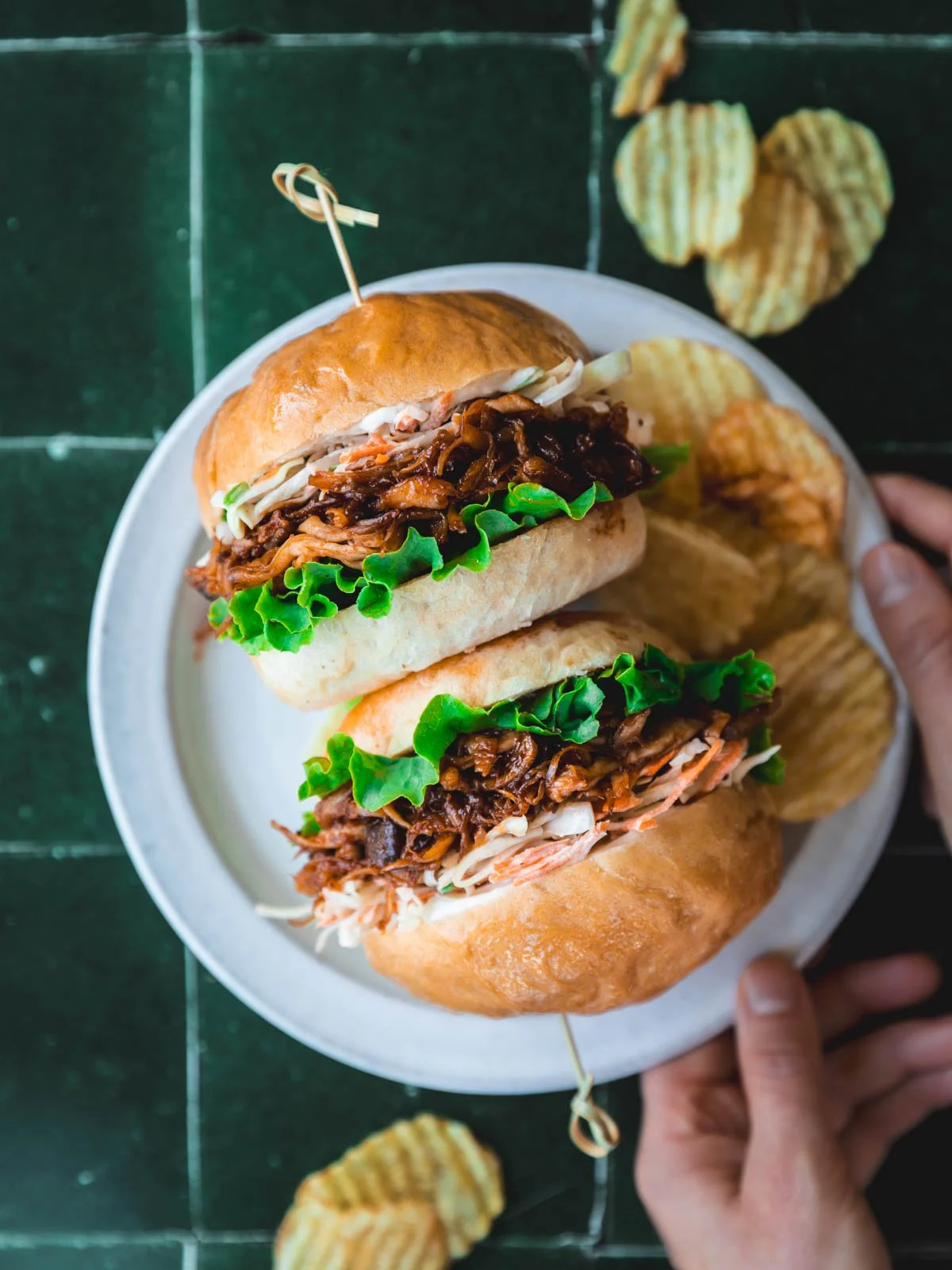 Vegan BBQ pulled pork sandwich with a side of chips.