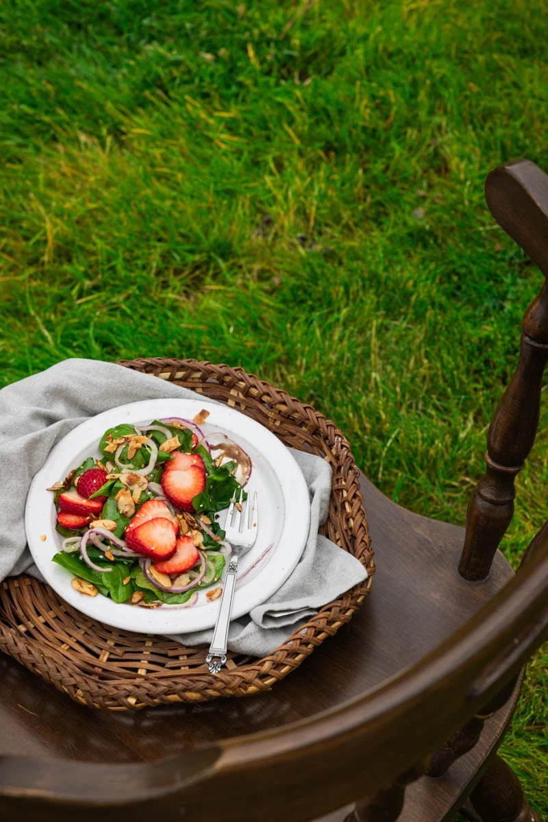 vegan spinach salad with strawberries outside on a chair