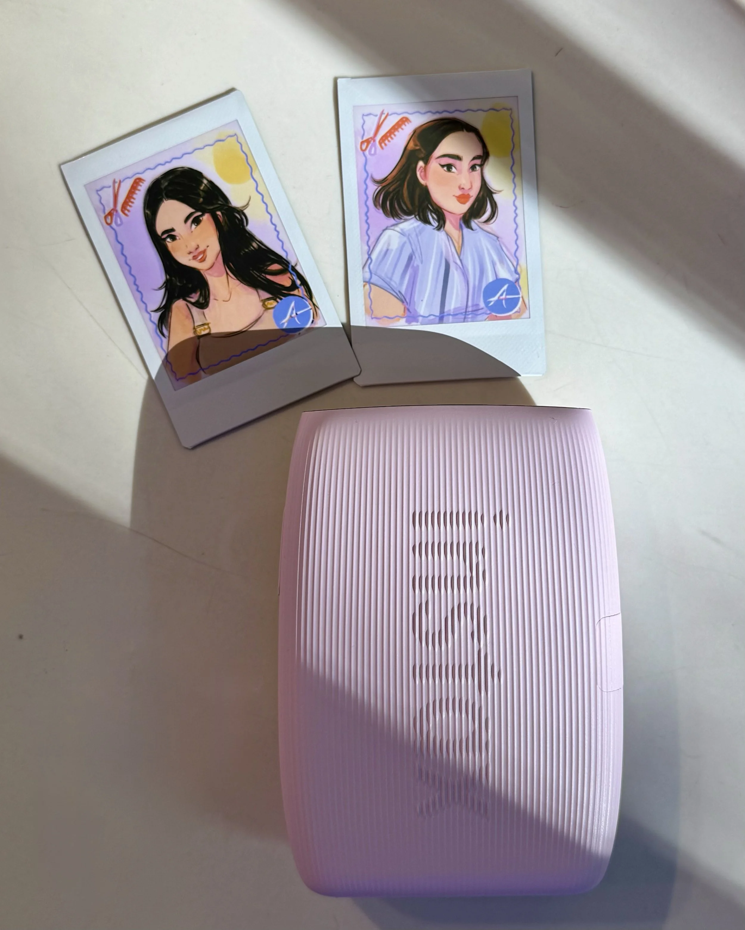 Two illustrated portraits of women, each in a vertical Polaroid-style frame with a purple border. One woman has long, dark hair and is wearing a brown top, while the other has shoulder-length dark hair and is wearing a light blue shirt. Both images have a background with a yellow sun, a red comb and scissors, and a blue circle with a white logo.