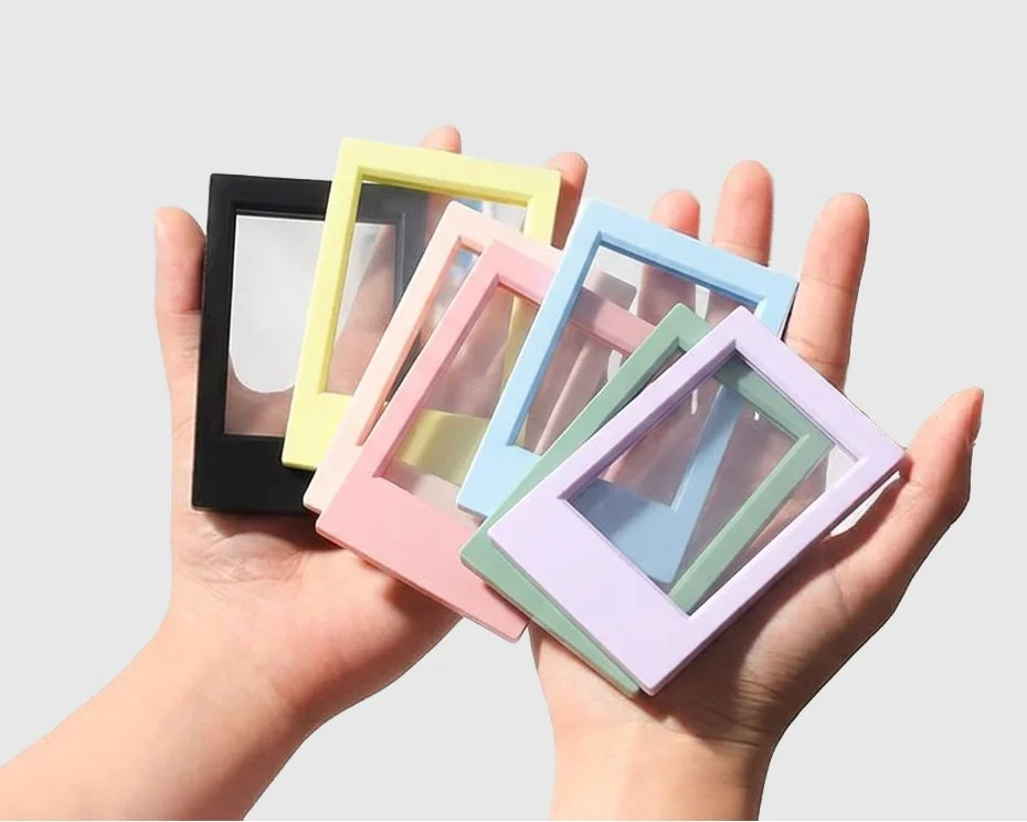 Person holding several pastel-colored photo frames in black, yellow, pink, blue, green, and purple.