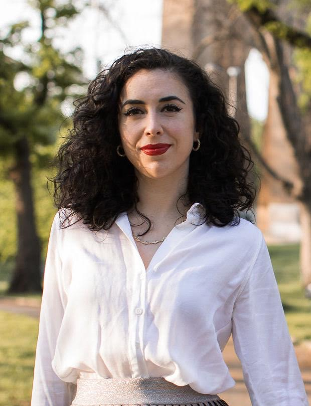 A young man smiling, wearing a hoodie, in black and white.