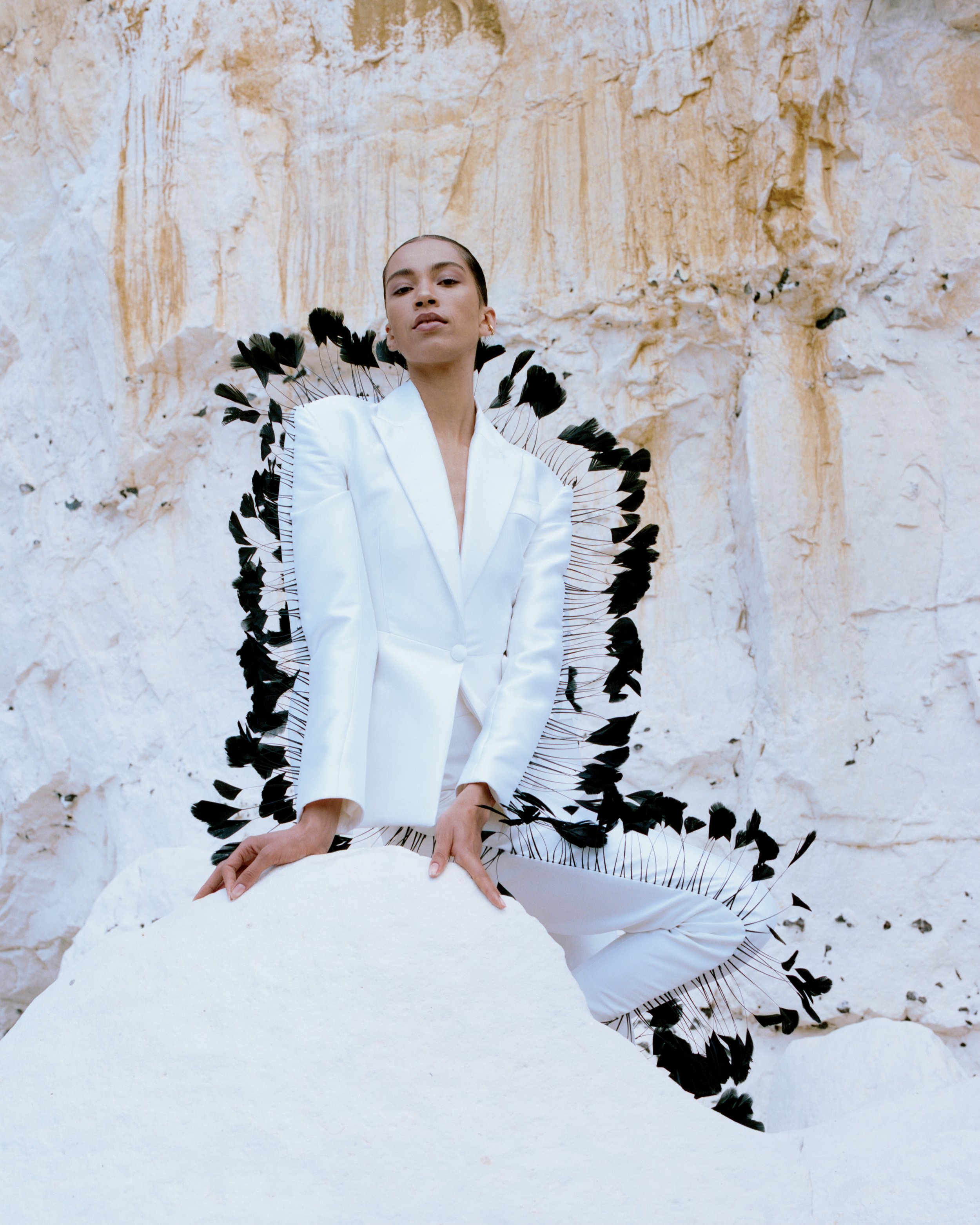 mixed race woman wearing a white silk tuxedo with feather details