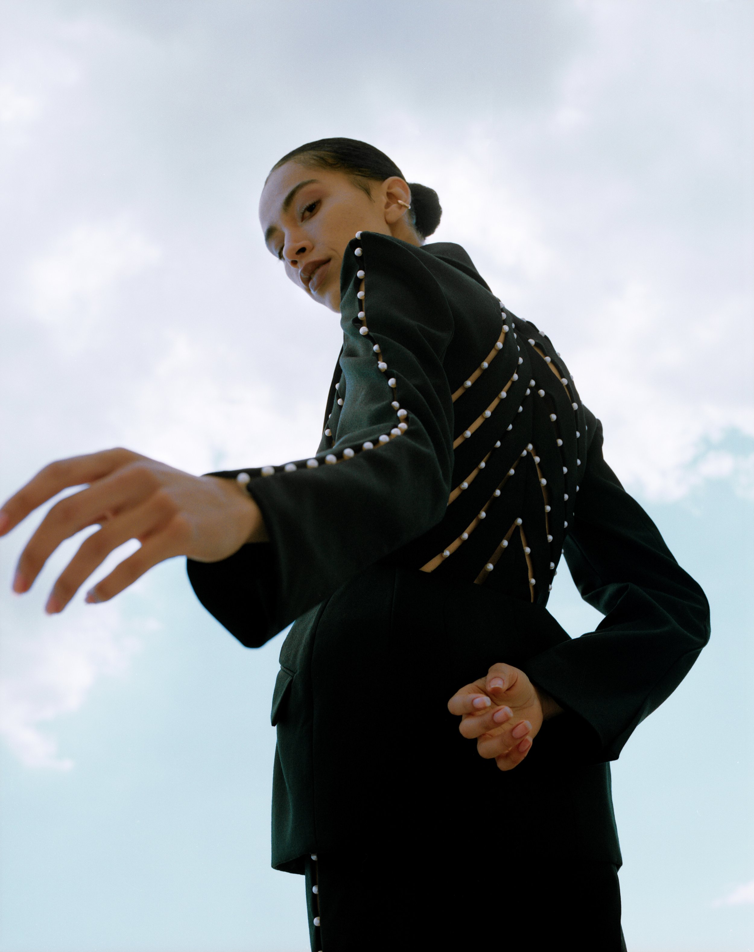 back view of mixed race woman wearing a black tuxedo with pearl details