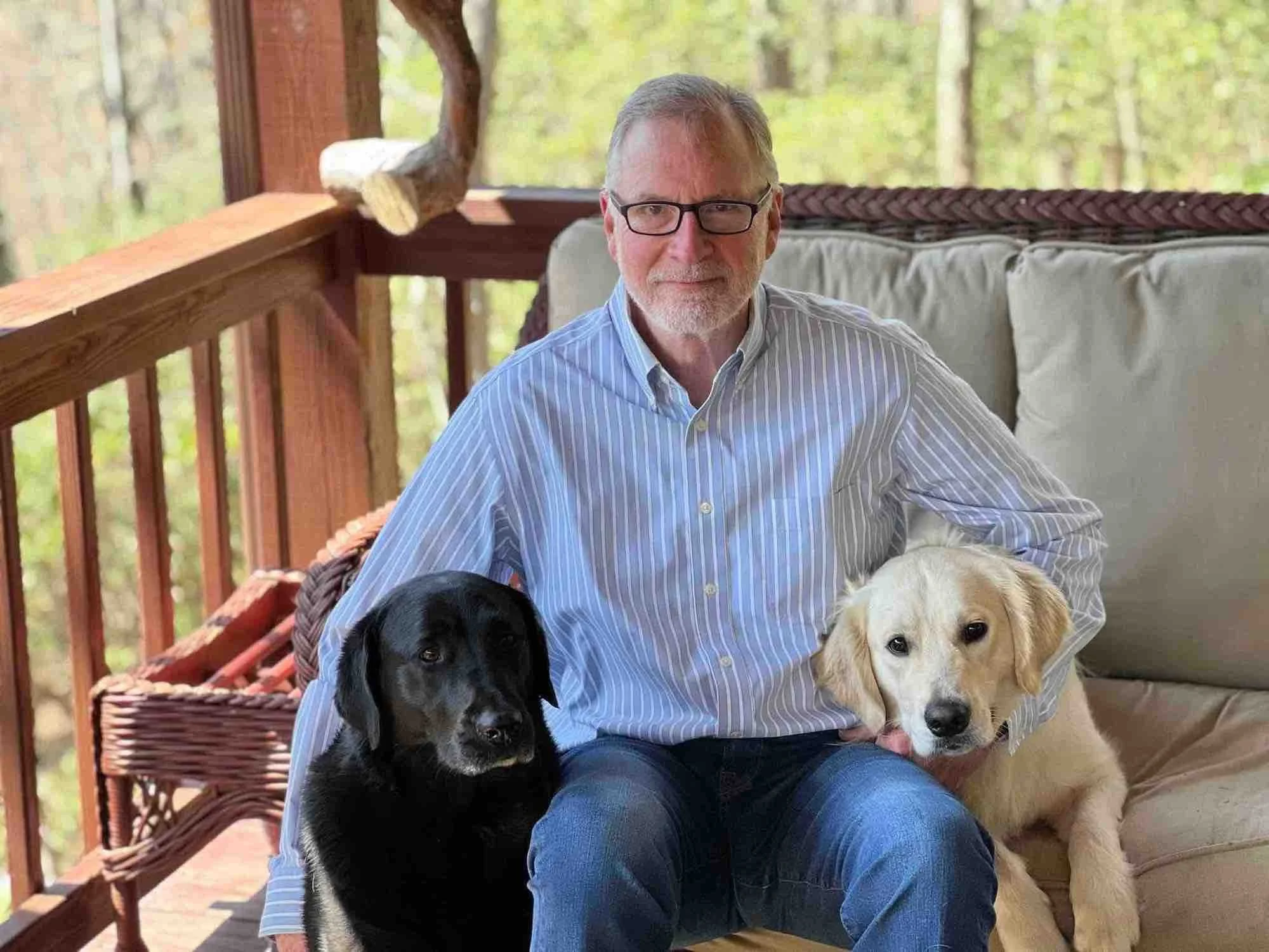 Bert sitting on back deck with his two dogs, Bear and Finley