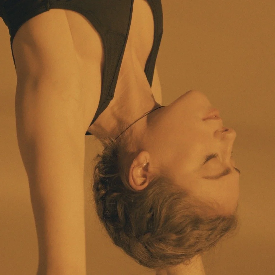 A woman with short hair lying on her side with her eyes closed, wearing a black sleeveless top.