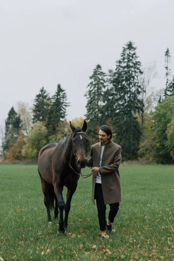 man walking horse in field