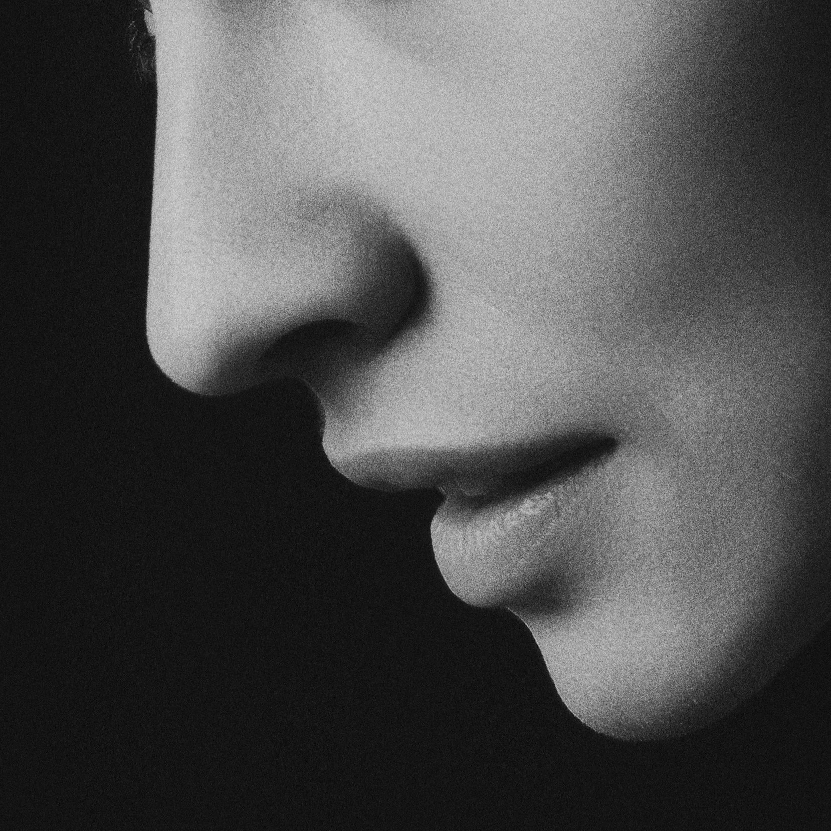 Close-up black and white photo of a person's face, focusing on the nose, lips, and part of the cheek.