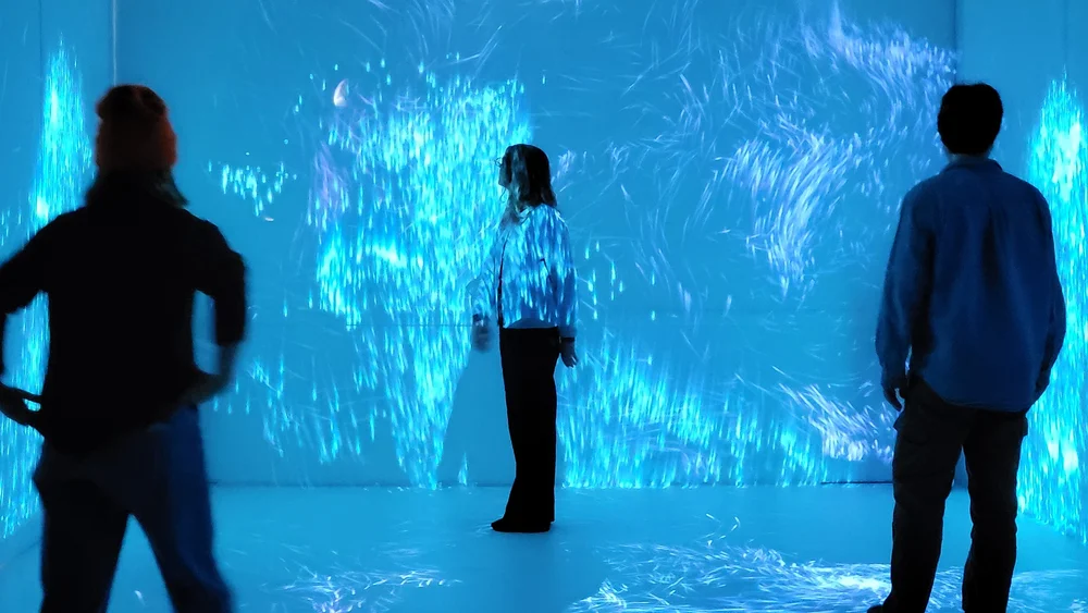 Visitors standing inside a blue immersive projection in the Dream Lounge