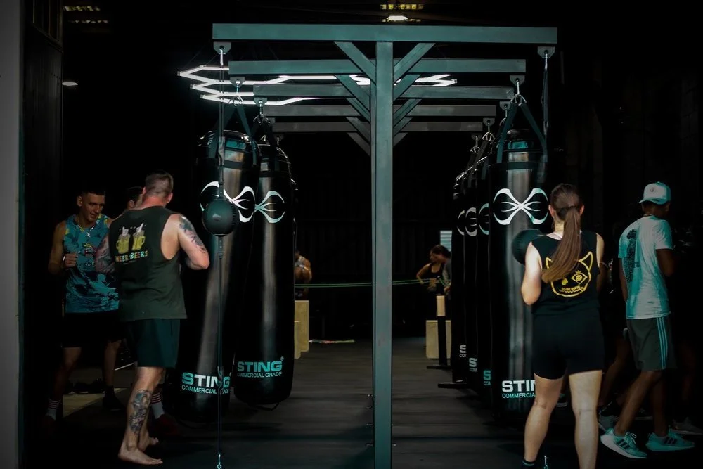 People practicing boxing with punching bags in a gym.
