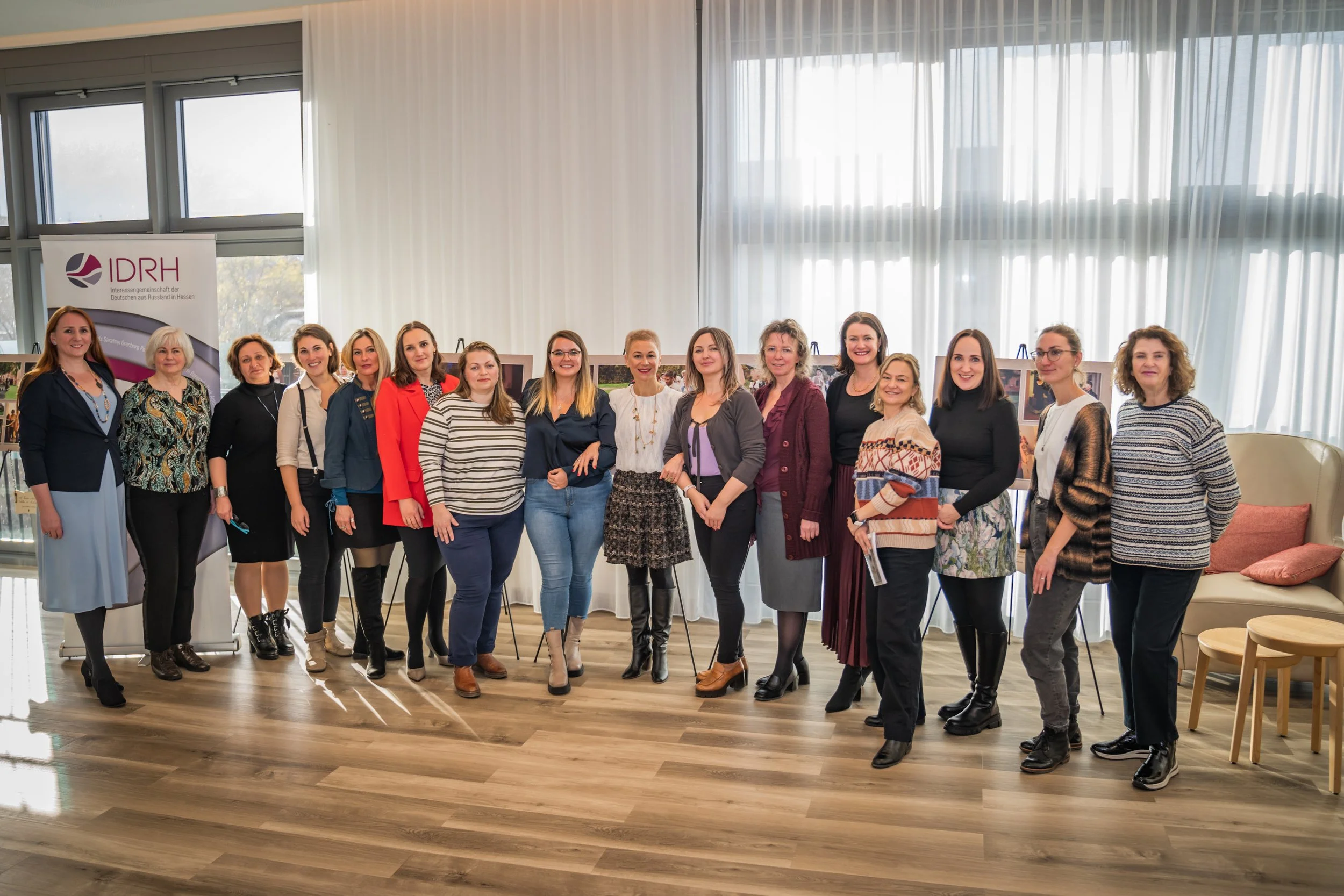 Gruppe von Frauen, die in einem Raum für eine Fotografie posieren, mit einem IDRH-Stand im Hintergrund.