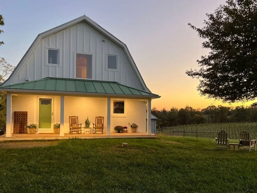 Guest house with two chair out front with a sunset in the background.