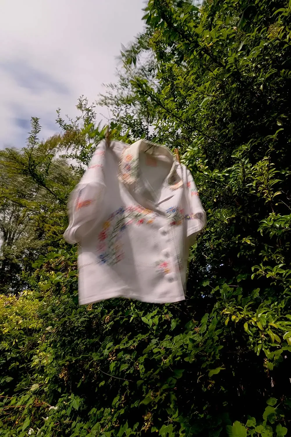Soft blur or movement of a custom made tablecloth blouse hanging in a tree.