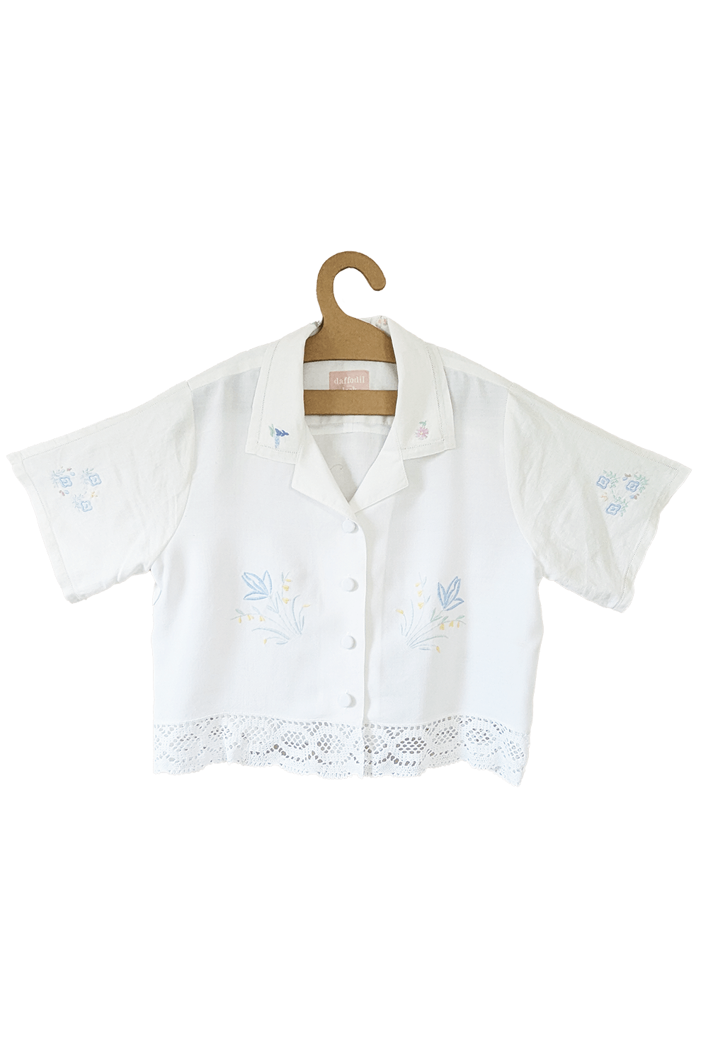 White blouse with lace hem and delicate embroidery.