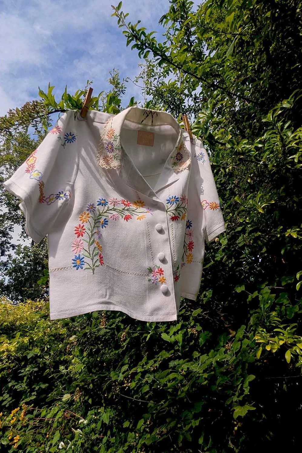 Boxy short-sleeved shirt made from a reclaimed white vintage tablecloth with engineered floral embroidery.