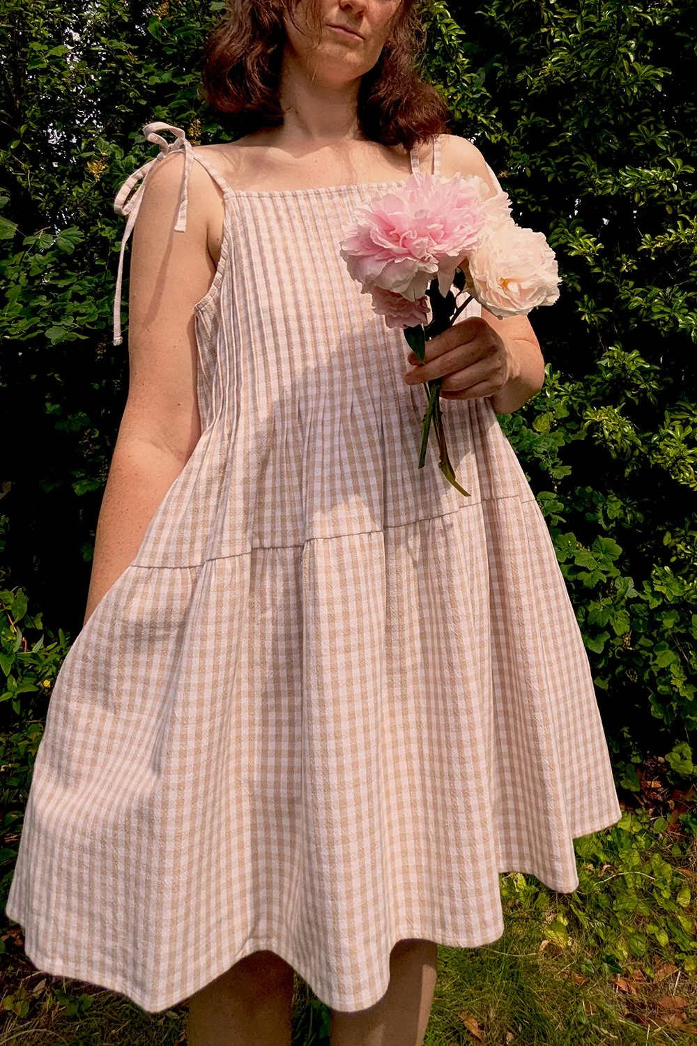 Tiered sleeveless summer dress in beige and white gingham check with delicate shoulder tie straps.
