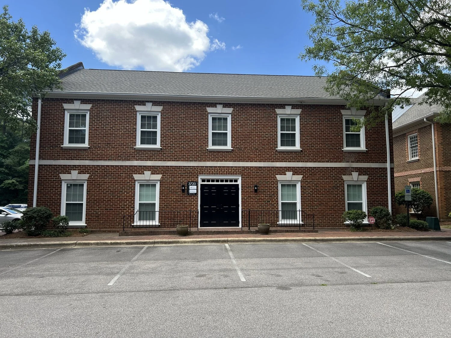 An image of our office which is a brick building, 2 stories, double black doors with ramp entry and plenty of parking.