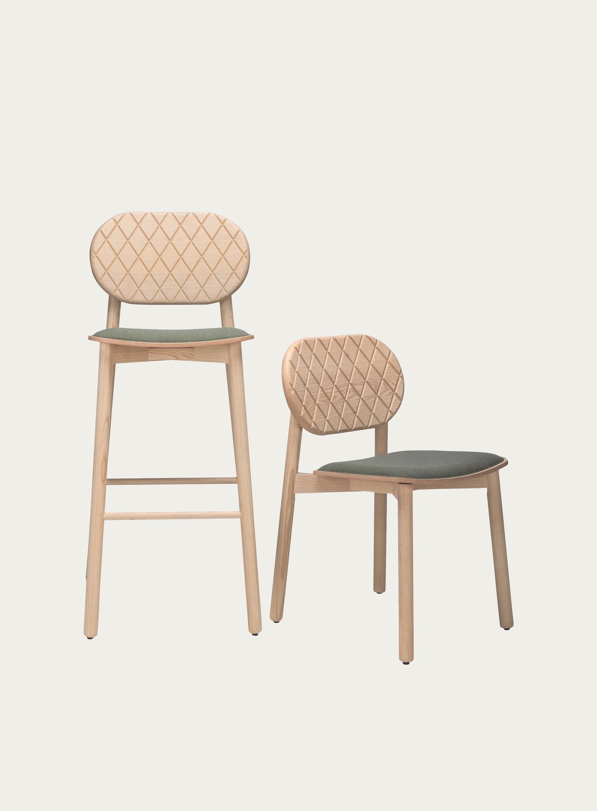 Two modern wooden chairs with padded seats and geometric-patterned backrests, one on a tall stool and the other like a regular chair, against a plain background.