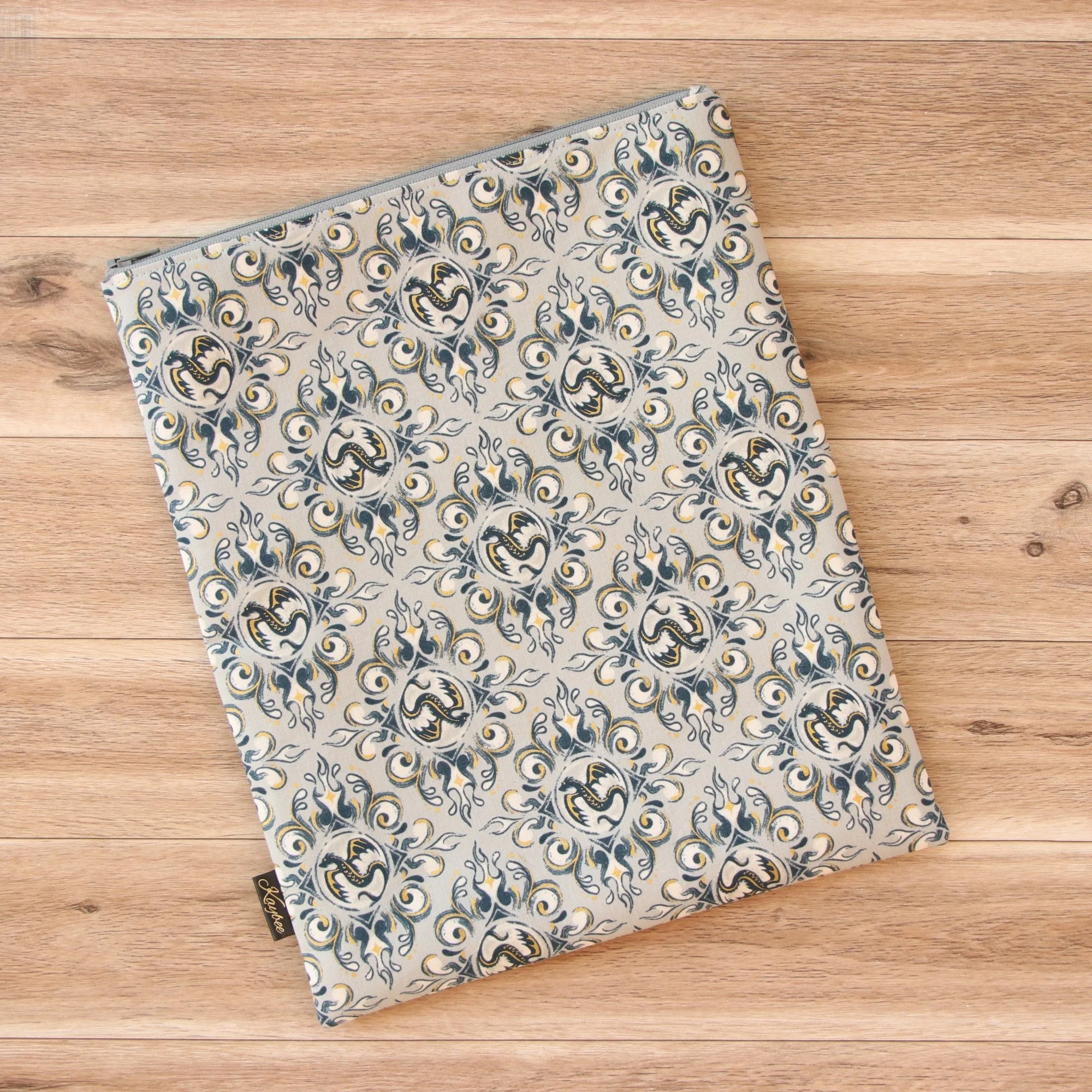 Large handmade dragon book sleeve in gray designer fabric with a premium YKK zip on a wooden background.