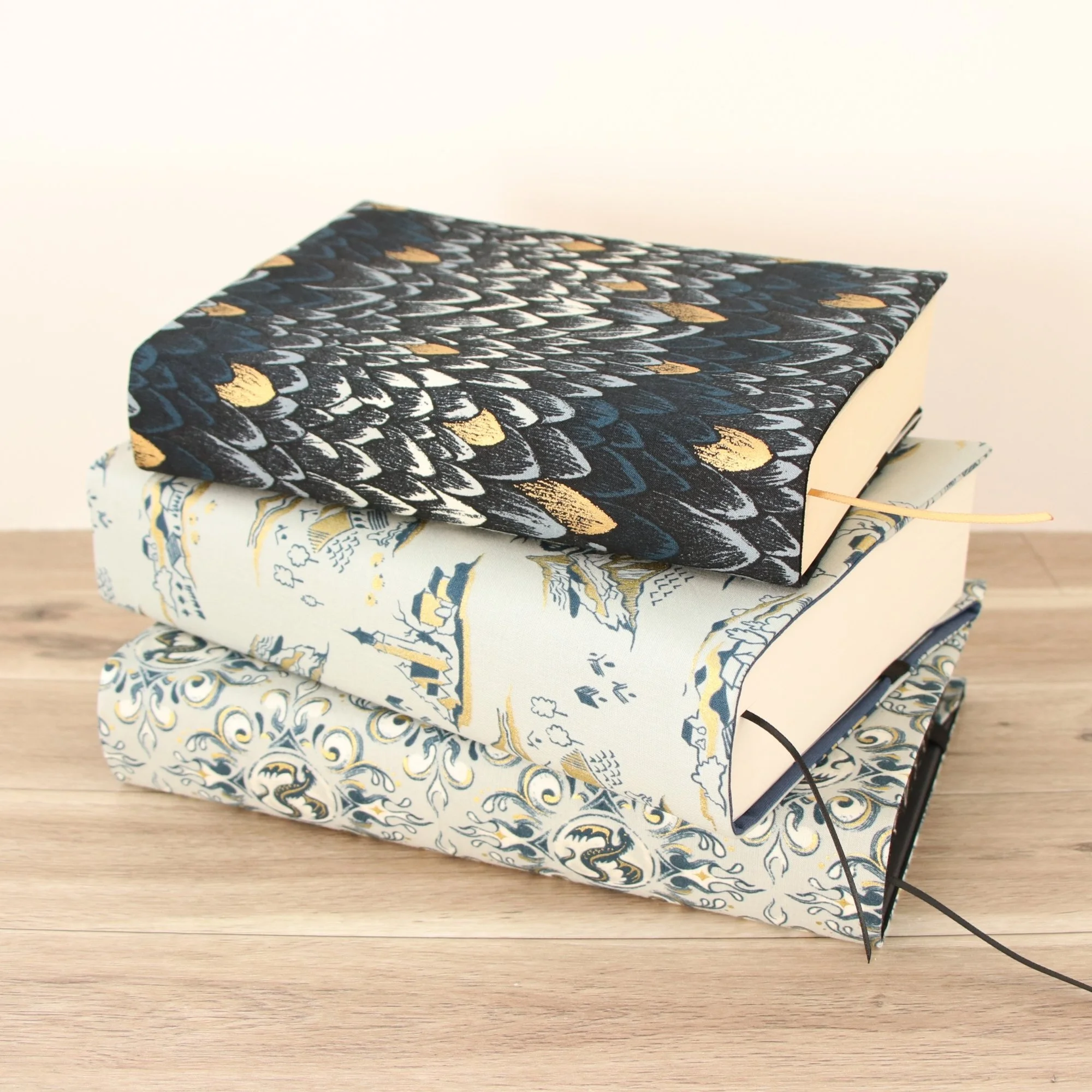 Stack of handmade First Edition Book Jackets in coordinating fantasy-inspired fabrics, custom made in New Zealand.