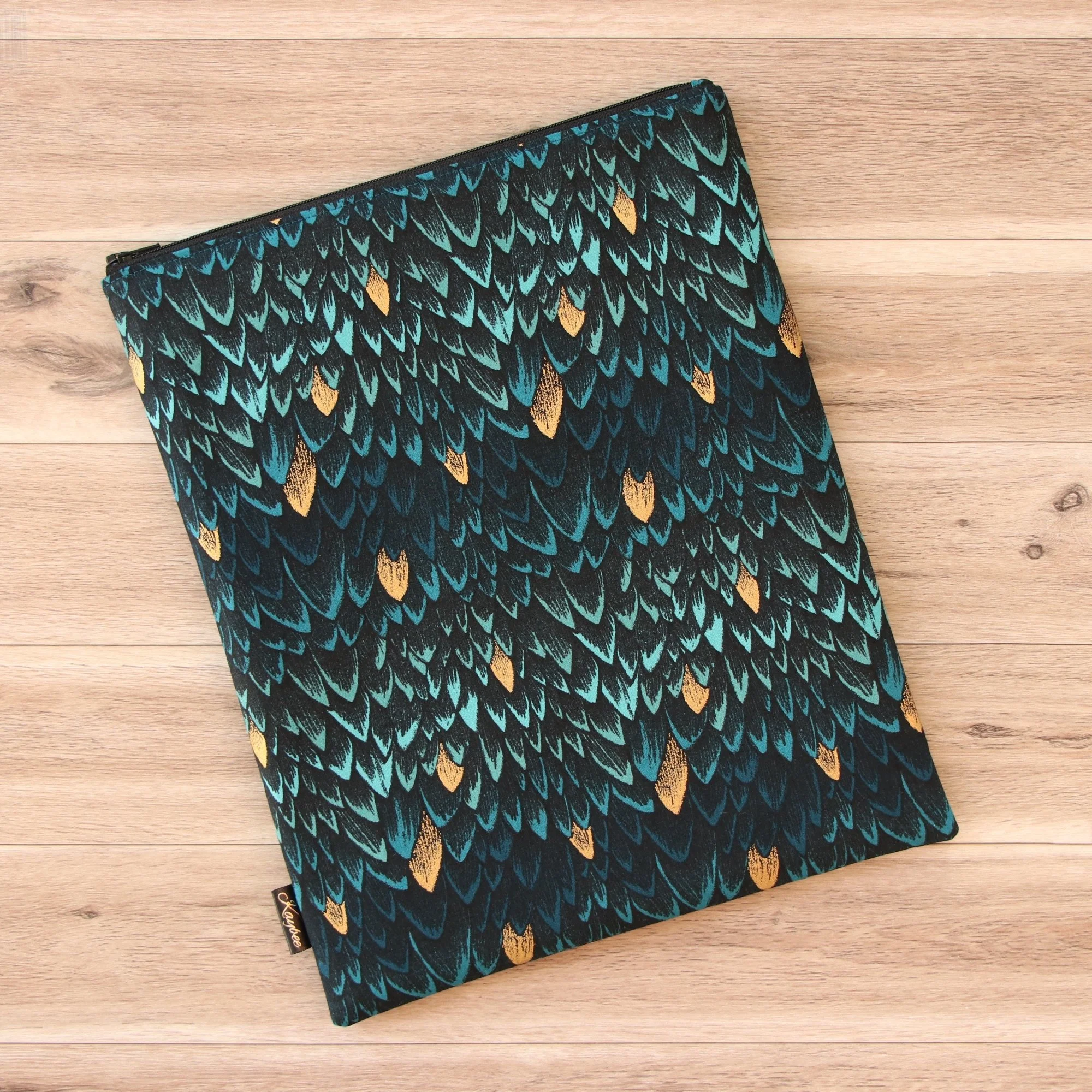 Large handmade dragon book sleeve in teal designer fabric with a premium YKK zip on a wooden background.
