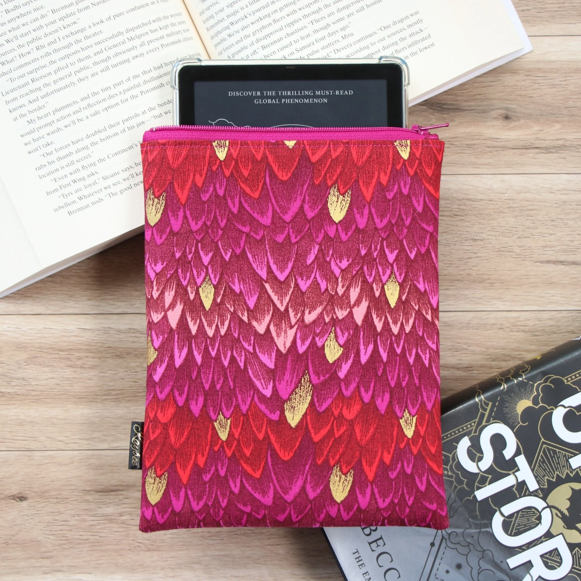 Handmade First Edition Kindle Sleeve with dragon-inspired fabric beside books.