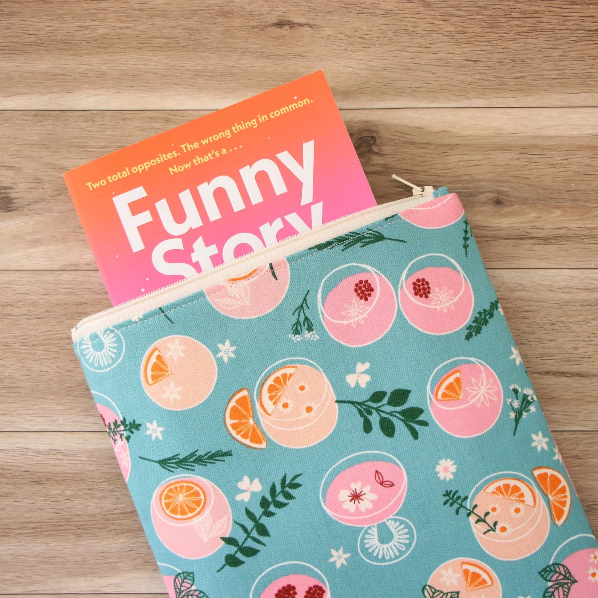 Classic Book Sleeve in blue cocktail print fabric showing a paperback partially inside the zippered sleeve.